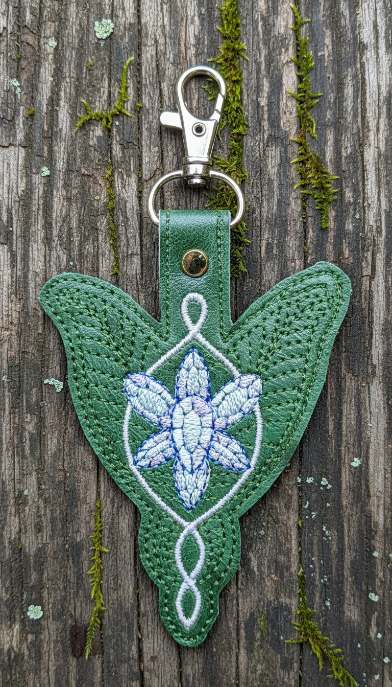 Green keychain with embroidered design on a wooden background