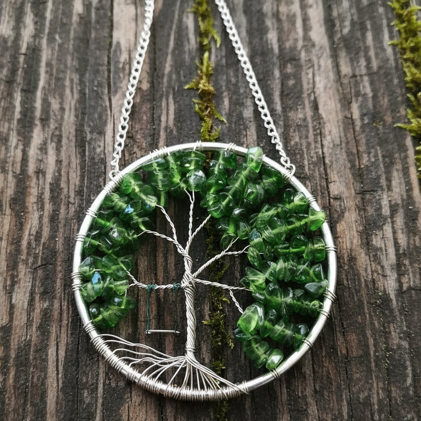 A silver ring with green glass chips shaped into a tree of life, with tarnish resistant silver wire and a tiny swing.