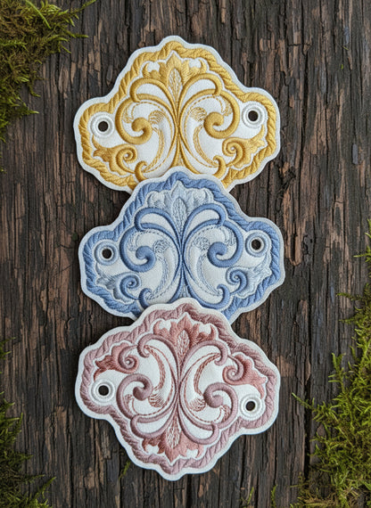 Three hair holders with floral filigree patterns in blue, yellow, and pink colors, made with Egyptian cotton stitching.