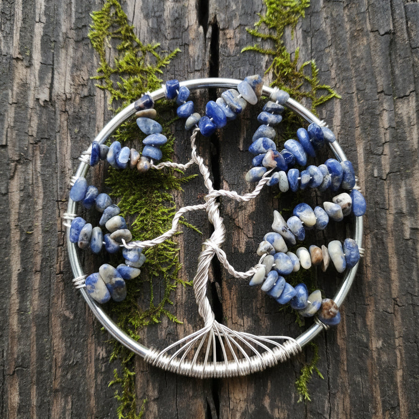 A sodalite crystal suncatcher in the shape of a tree, with a silver wire frame and sodalite stones set within a circular form.