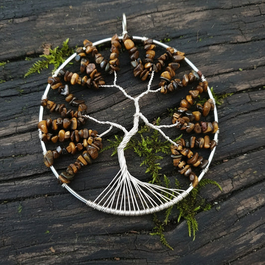 A handmade suncatcher featuring silver rings with tiger's eye crystals arranged to form a tree of life shape.