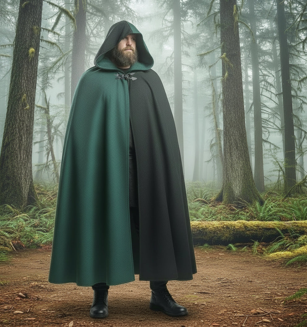 Man wearing a green and black hooded cloak against a mountainous landscape