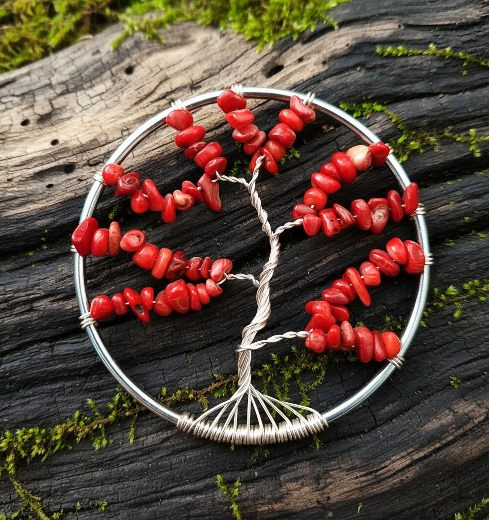 A circular suncatcher with red coral crystals arranged in the shape of a tree with silver wire on a black background.